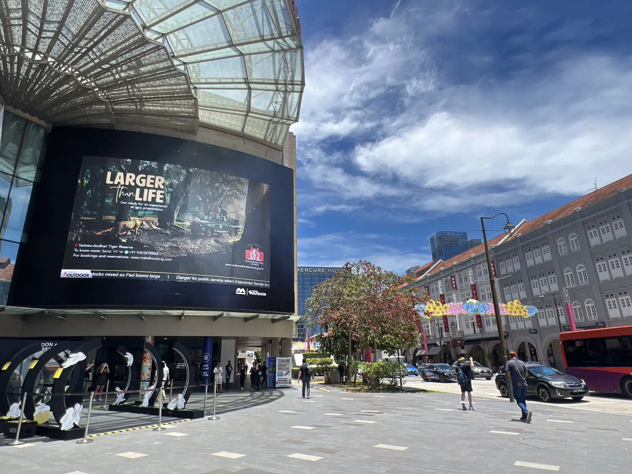 Large outdoor LED billboard running a tourism campaign above a city street