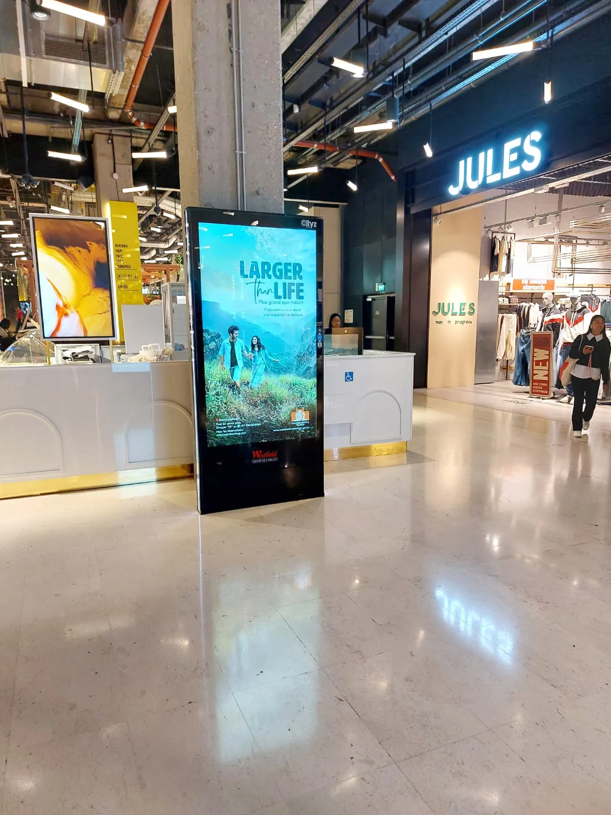 Digital out-of-home screen running a campaign in a shopping centre concourse